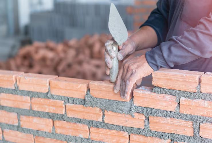 Mason packing fresh mortar into brick joints with a trowel